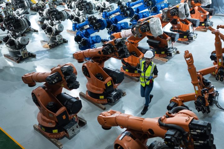 a-female-engineer-installs-a-program-on-a-robotics-arm-in-a-robot-warehouse-.jpg