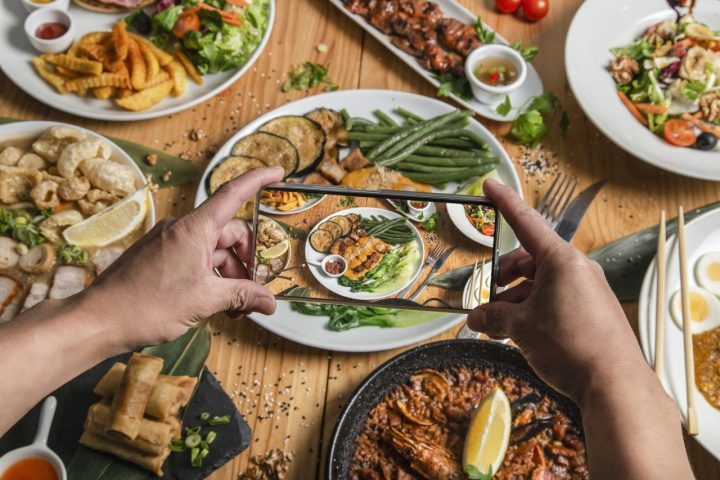 a-man-takes-a-photo-of-food-on-his-smartphone-at-a-filipino-restaurant-he-shares-your-lifestyle